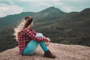 femme assise seule sur une colline qui regarde l'horizon