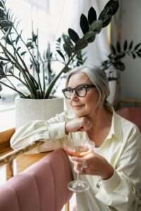 femme a lunette reflechit verre de vin a la main