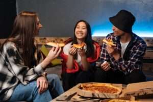 3 asiatiques qui mangent une pizza, 2 femmes et 1 homme