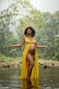 Femme enceinte portant une robe jaune et une couronne posant dans l'eau