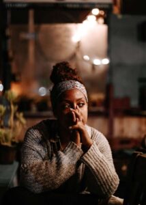 Une femme assise dans un bar vide réfléchit a la dispute avec son partenaire de manière constructive